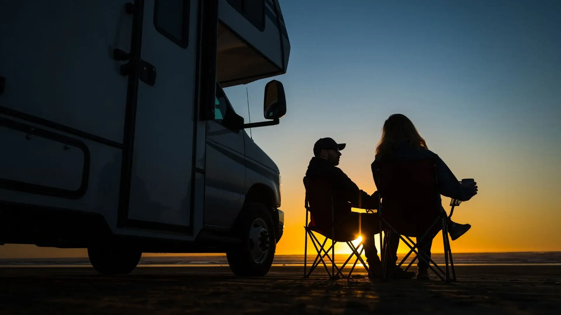 Couple by RV at sunset on beach